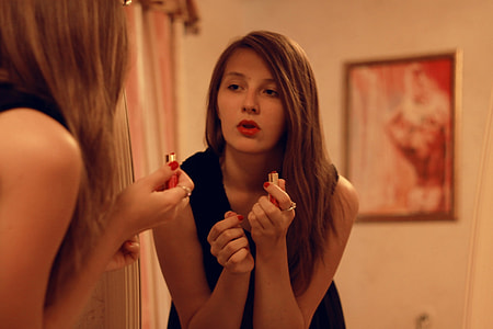 woman holding red lipstick while wearing sleeveless tops thumbnail