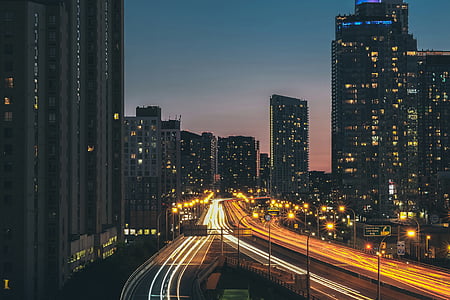 time-lapse photography of road between high rise buildings during blue hour thumbnail