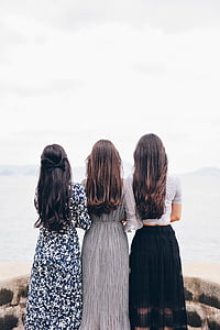 three women standing beside body of water during daytime thumbnail