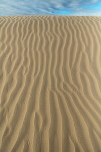 sand dunes under cloudy sky during daytime thumbnail