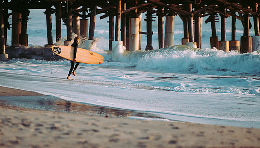 walking man holding surfboard going to beach at daytime thumbnail