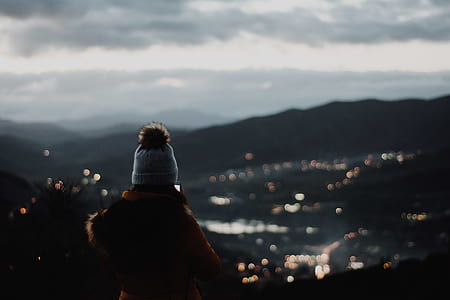 woman wearing white and brown bobble beanie looking at city thumbnail
