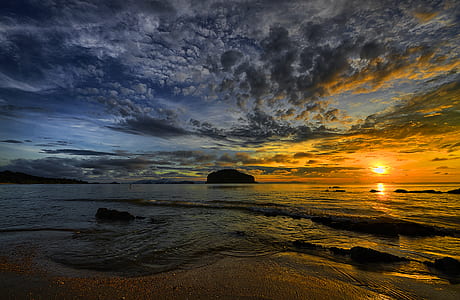 silhouette of islet on the body of water under blue sky with gray clouds during daytime thumbnail