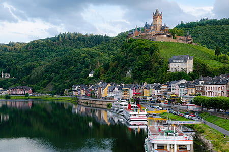 brown castle on top of mountain under with multicolored painted buildings near body of water thumbnail