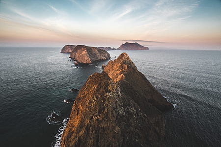 five separate islands with no vegetation surrounded by calm water at daytime thumbnail
