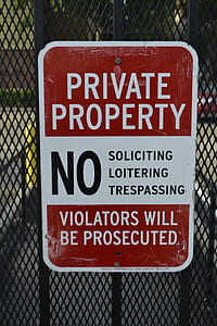 brown and white private property signage on black metal fence thumbnail