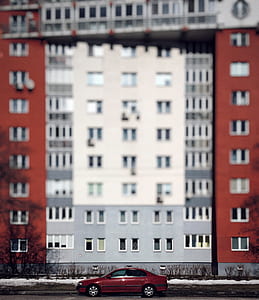 red sedan in front of gray concrete building thumbnail