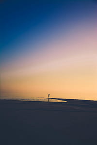 person walking on beach sand under clear sky thumbnail