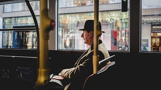 sitting man wearing black coat and bowler hat inside vehicle thumbnail