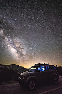 grey SUV on gray asphalt round under starry sky thumbnail