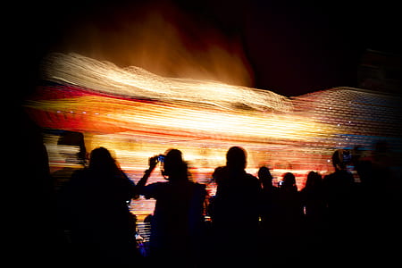 timelapse photo of people's silhouette against yellow and red lights thumbnail
