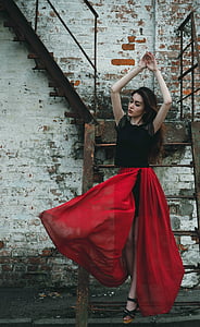 woman in black and red short-sleeved dress standing beside brown metal stairs during daytime thumbnail