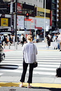 woman standing near pedestrian lane with black car running at daytime thumbnail