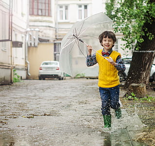 time lapse photography of boy holding umbrella on body of water thumbnail