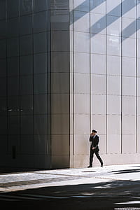 person walking beside gray concrete building at daytime thumbnail