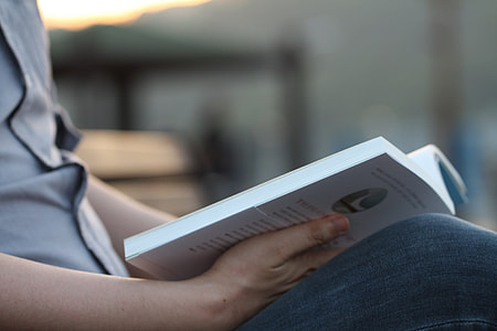 person reading while holding book on lamp thumbnail