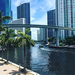 boat under concrete bridge and buildings in distance thumbnail