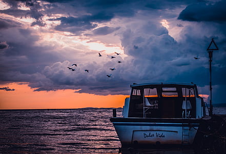 landscape photography of boat, sky, and body of water thumbnail