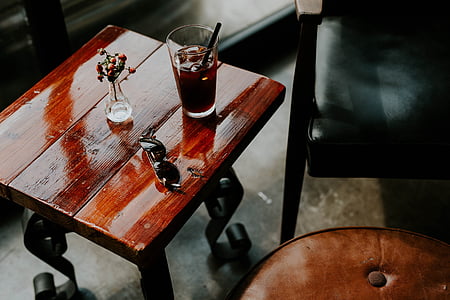 drinking glass beside vase and sunglasses on table thumbnail