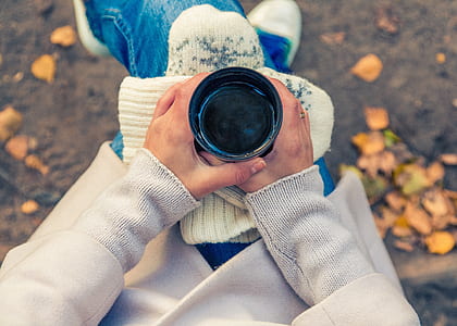 person holding black cup while sitting on chair thumbnail