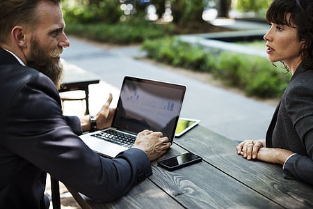 man and woman in black suit sitting in front of table thumbnail