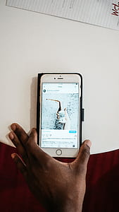 person holding gold iPhone 6 with black case on white table thumbnail