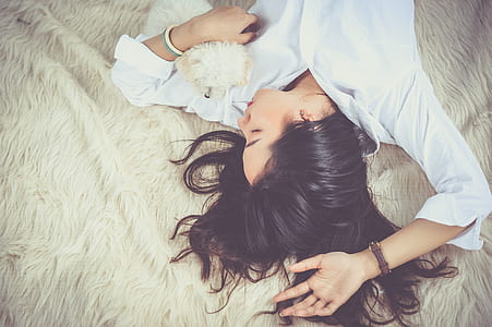 woman in white dress shirt lying on brown textile thumbnail