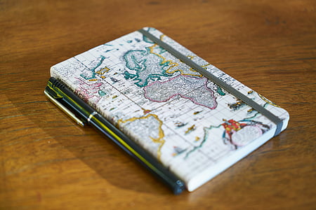white map covered book and pen on brown wooden surface thumbnail