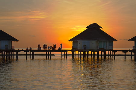 people standing on dock between houses at golden hour thumbnail