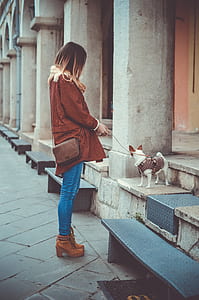 woman holding dog leash with dog near the building thumbnail