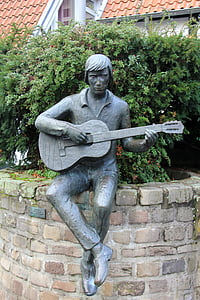 man playing guitar while sitting black statue thumbnail