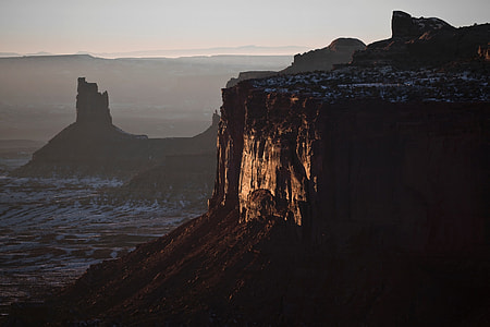 seawaves crashing with sunlight reflecting on rock mountain under foggy weather thumbnail