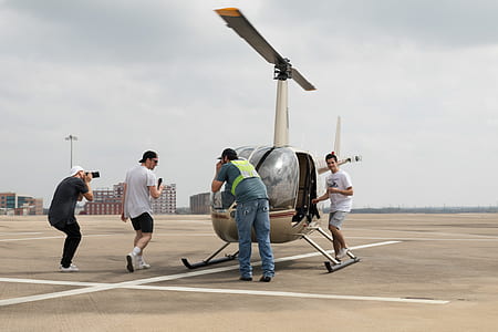 four men standing beside white helicopter under white clouds at daytime thumbnail