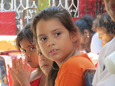 girl in orange top surrounded by people thumbnail