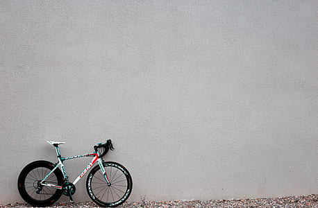 white and black road bicycle parked beside gray concrete wall thumbnail