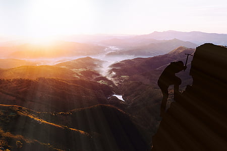 silhouette photo of person climbing on hill during sunset thumbnail