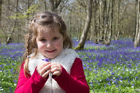 Girl in Red and Beige Jacket Holding Purple Petaled Flower thumbnail