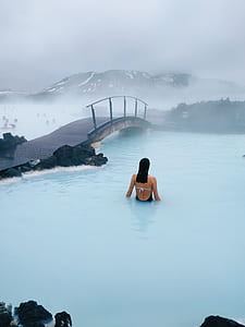 woman in body of water in front of pathway bridge photo thumbnail