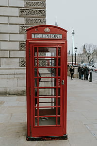 red telephone booth near wall thumbnail