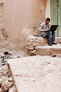 man sitting on gray concrete flooring usling laptop thumbnail