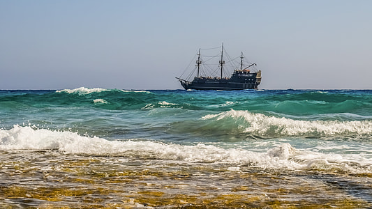brown sail ship anchored off shore thumbnail