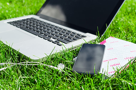 blck and white HP laptop beside black android smartphone on green grass thumbnail