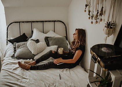 woman holding white ceramic mug sitting bed leaning on wall thumbnail