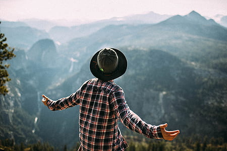 person opening arms facing mountain cliff thumbnail