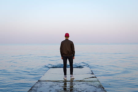 person standing on brown on near body of water thumbnail