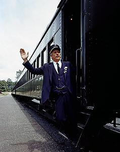 man standing beside black train during daytime thumbnail