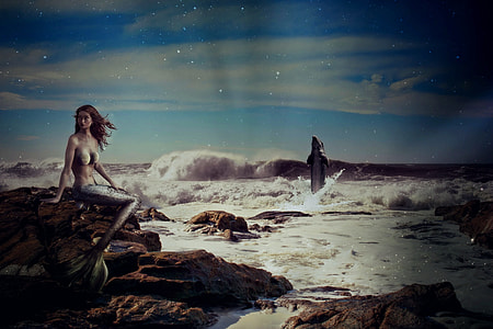mermaid sitting on rocks near body of water thumbnail