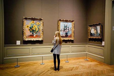 woman standing in front of three paintings thumbnail