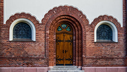 landscape photography of closed wooden arch door between two arch windows thumbnail