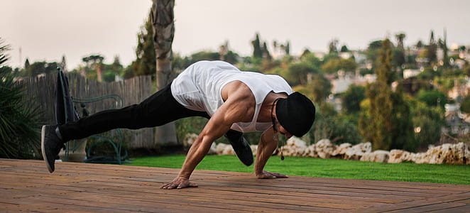 man planking on top of brown platform near green turf thumbnail